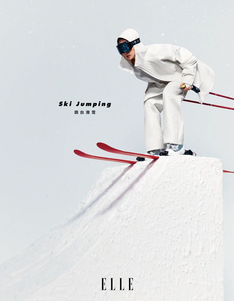 Fashion shot of a person in white ski gear, poised for ski jumping on a snow ramp, against a white background in a studio environment.