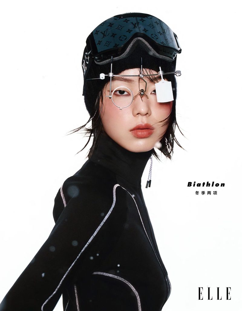 Portrait of an Asian woman with biathlon eyewear in a studio, wearing a black top against a clean white backdrop, fashion-forward style.