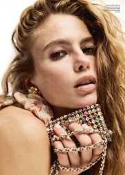 Close-up portrait of a woman holding a crystal-embellished handbag with a gold chain strap across her fingers.