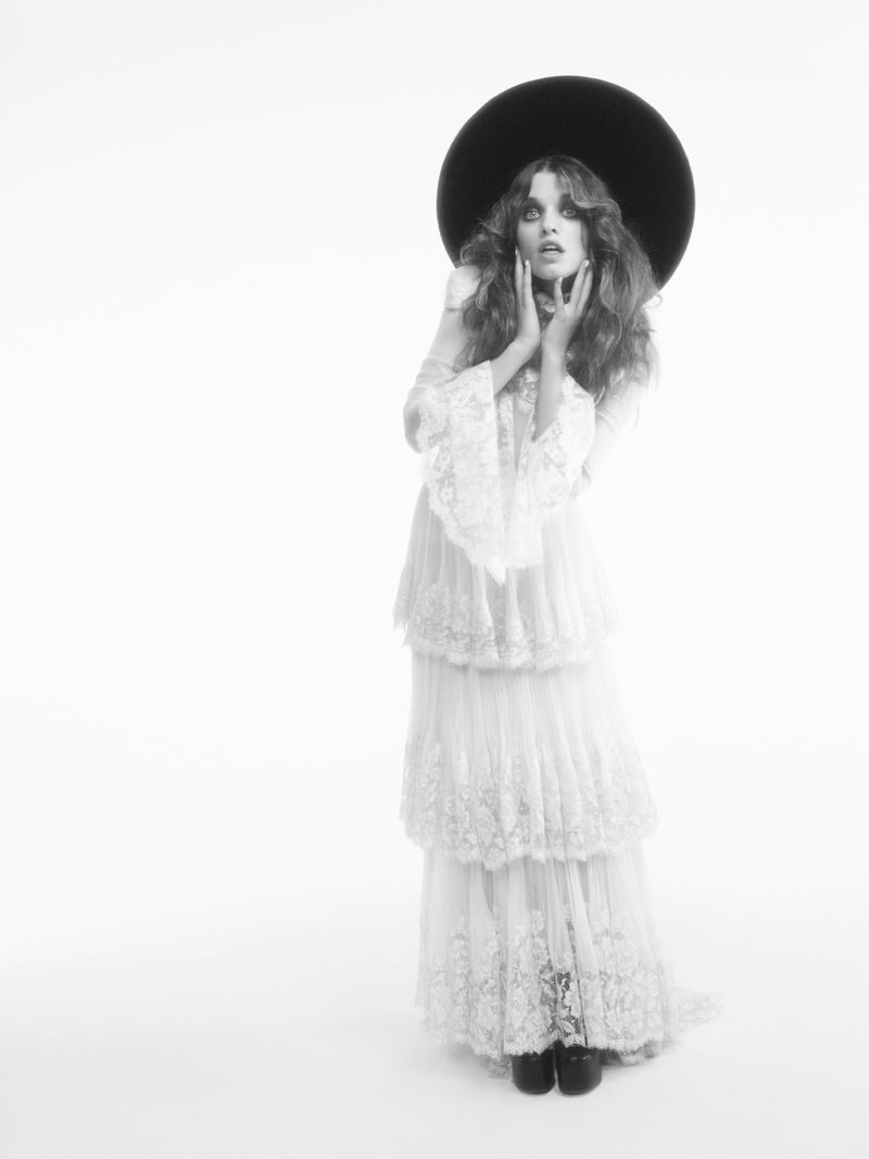 Ever Anderson wearing a tiered lace dress and wide-brimmed hat against a plain white background, photographed by Willy Vanderperre.