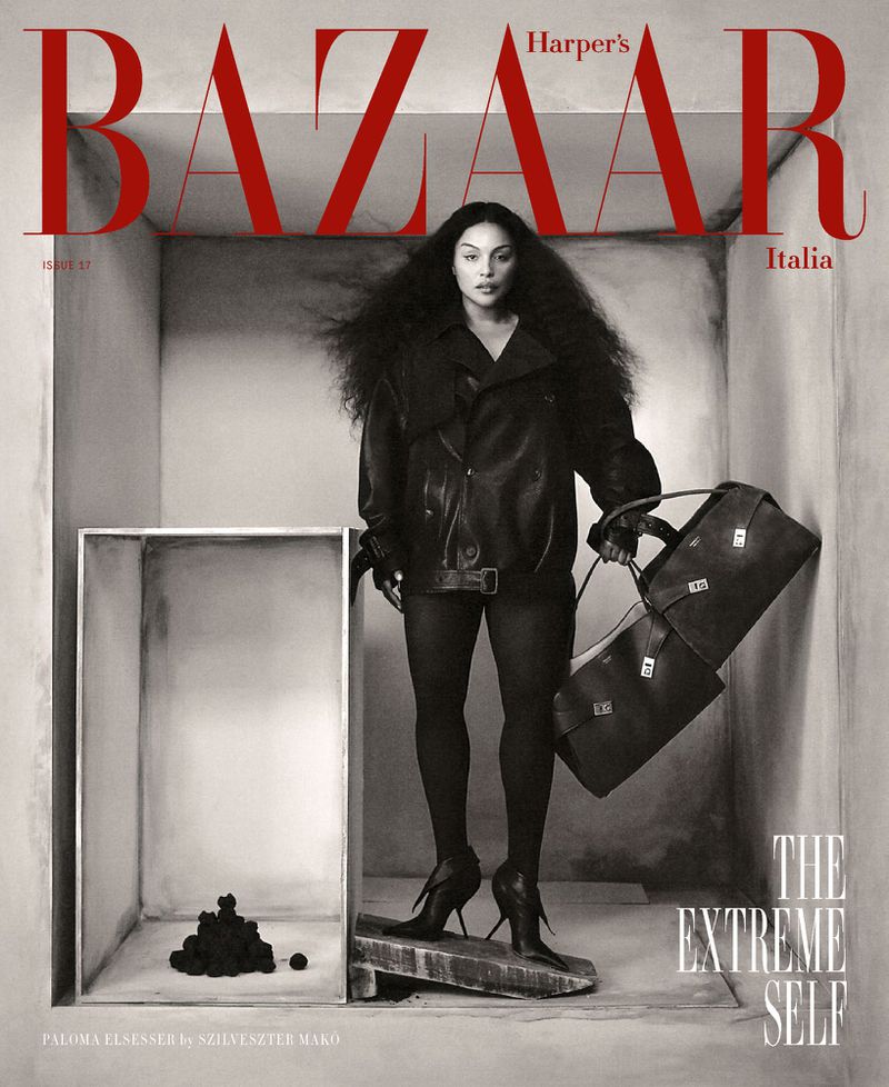 Fashion magazine cover featuring a woman with large hair, wearing a leather jacket and holding a duffel bag, in a box set.