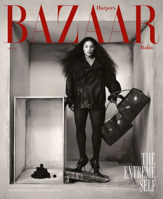 Fashion magazine cover featuring a woman with large hair, wearing a leather jacket and holding a duffel bag, in a box set.