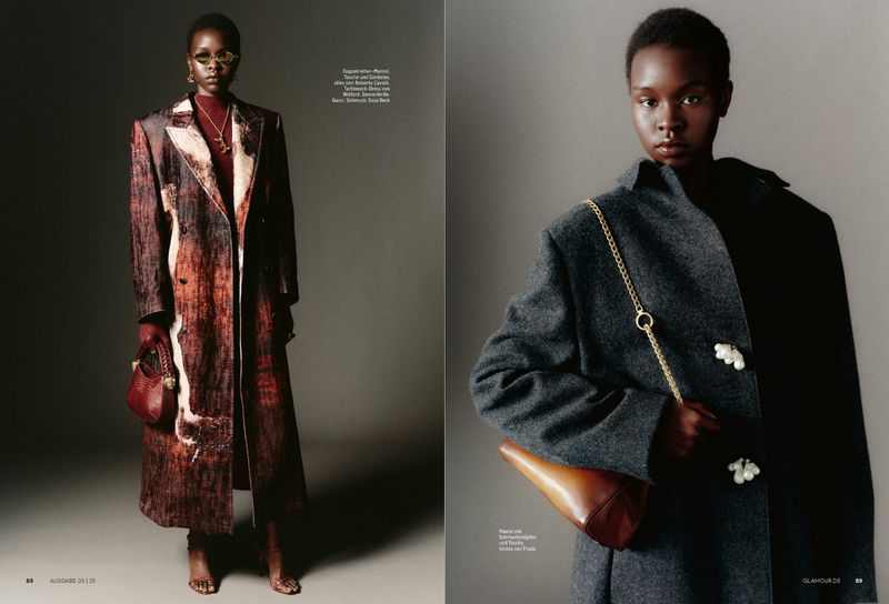 Model wearing a dark grey wool coat with decorative buttons and carrying a leather handbag with a gold chain strap