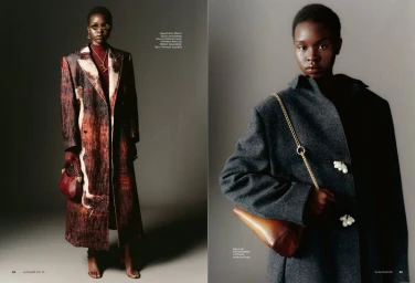 Model wearing a dark grey wool coat with decorative buttons and carrying a leather handbag with a gold chain strap