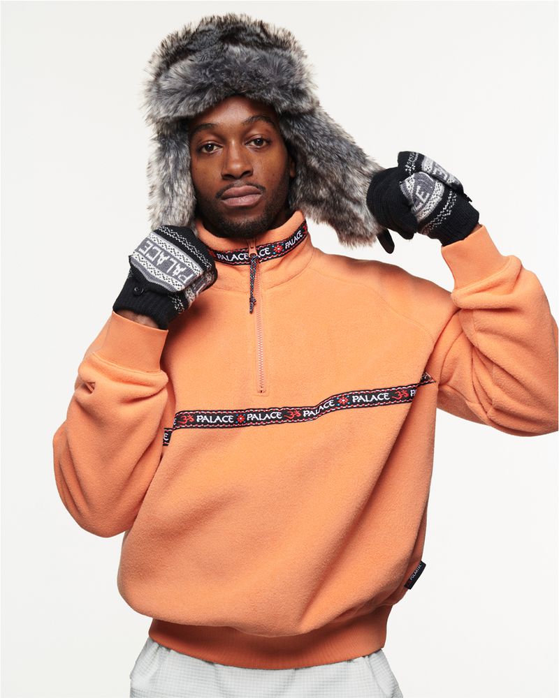 Fashionable adult male in a fleece jacket and fur hat poses indoors against a white background, showcasing stylish winter attire.