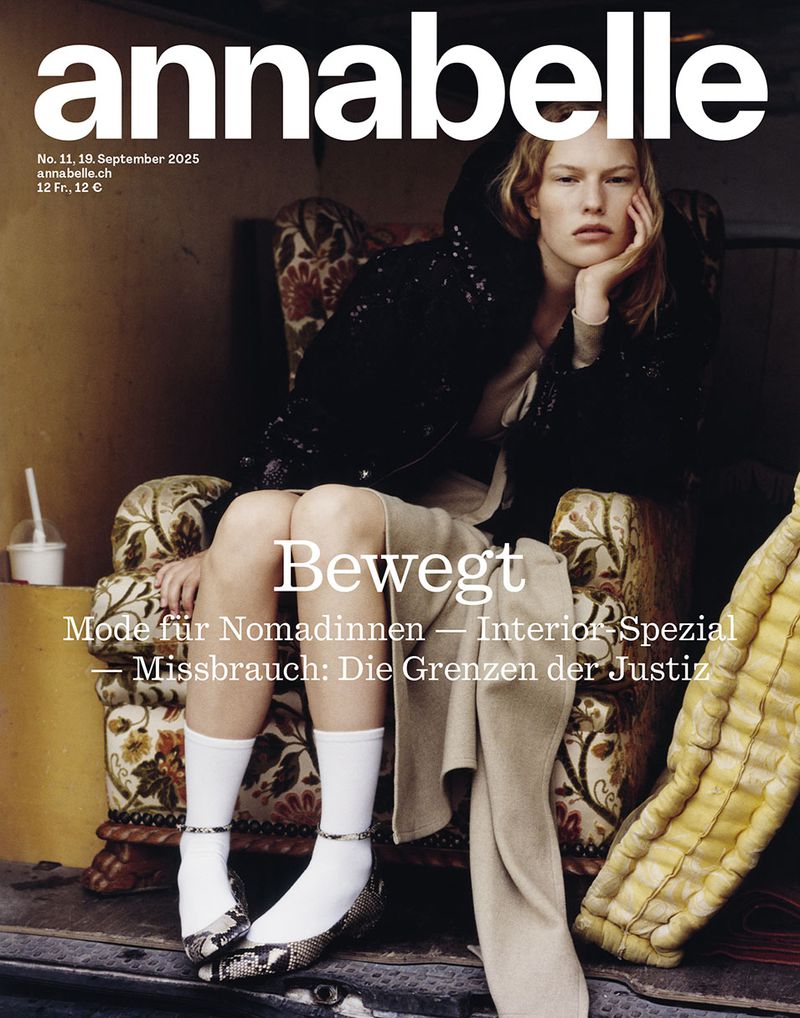 Magazine cover featuring a seated fashion model in a hooded jacket, white socks, and patterned shoes, with text overlay and ornate patterned chair.