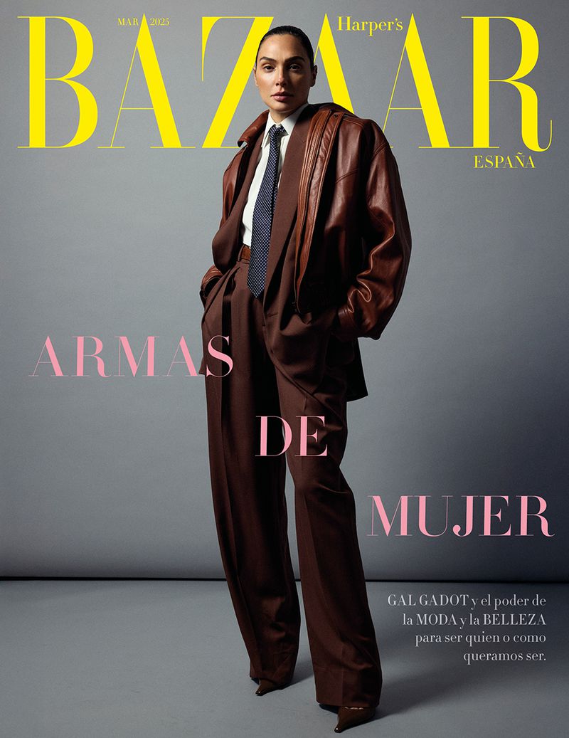 Gal Gadot on Harper's Bazaar Espana cover, March 2023. She is posing in a brown pantsuit, white shirt, and blue tie against gray background.