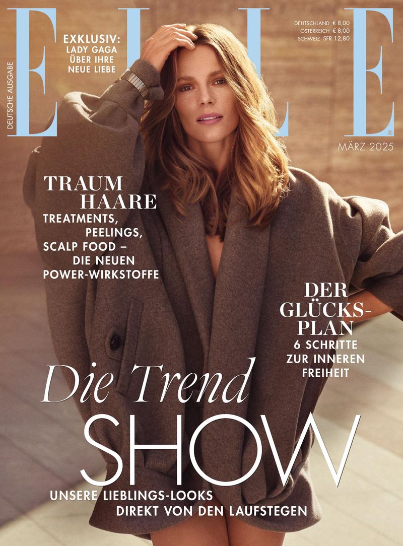 Elle magazine cover featuring a model in an oversized coat, with the magazine's title and headlines visible against a neutral background.