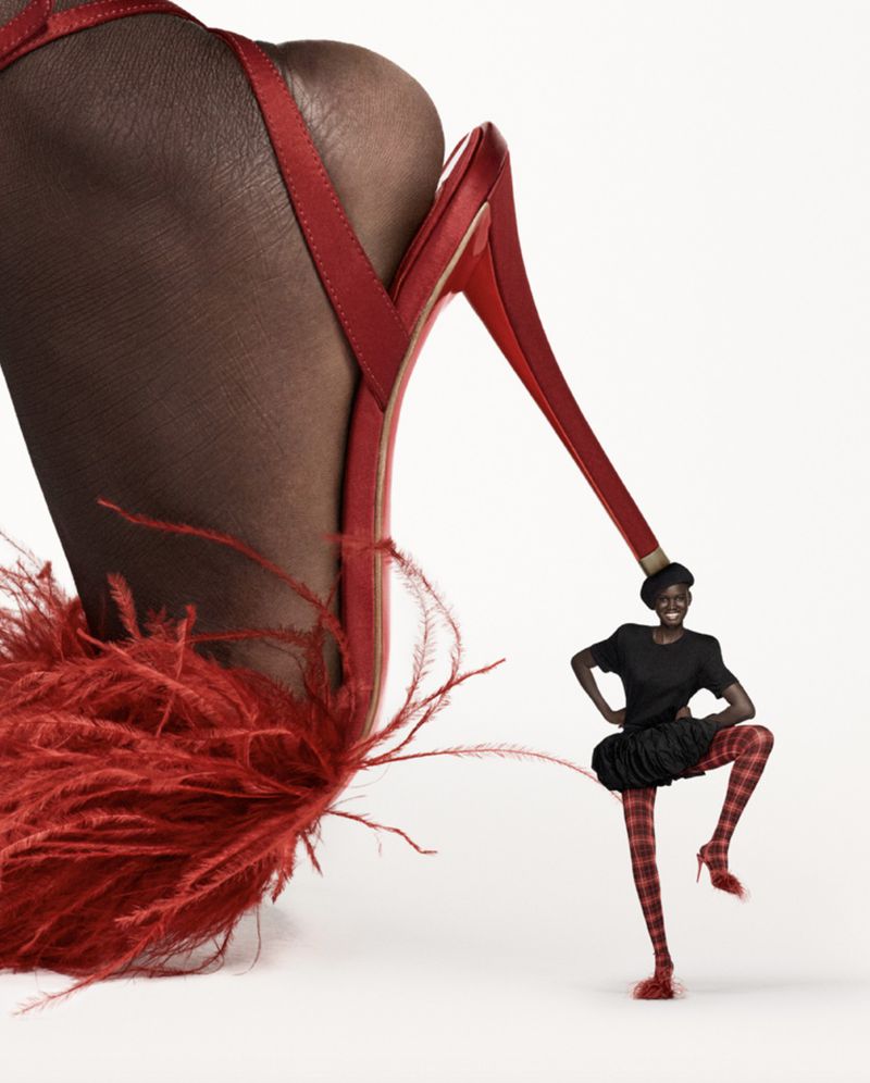 High-fashion visual featuring a large red, feathered high-heeled shoe next to a woman in red plaid tights posing with hands on hips.