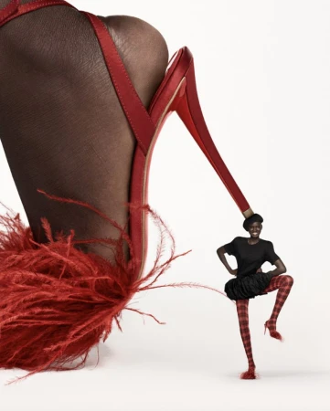 High-fashion visual featuring a large red, feathered high-heeled shoe next to a woman in red plaid tights posing with hands on hips.