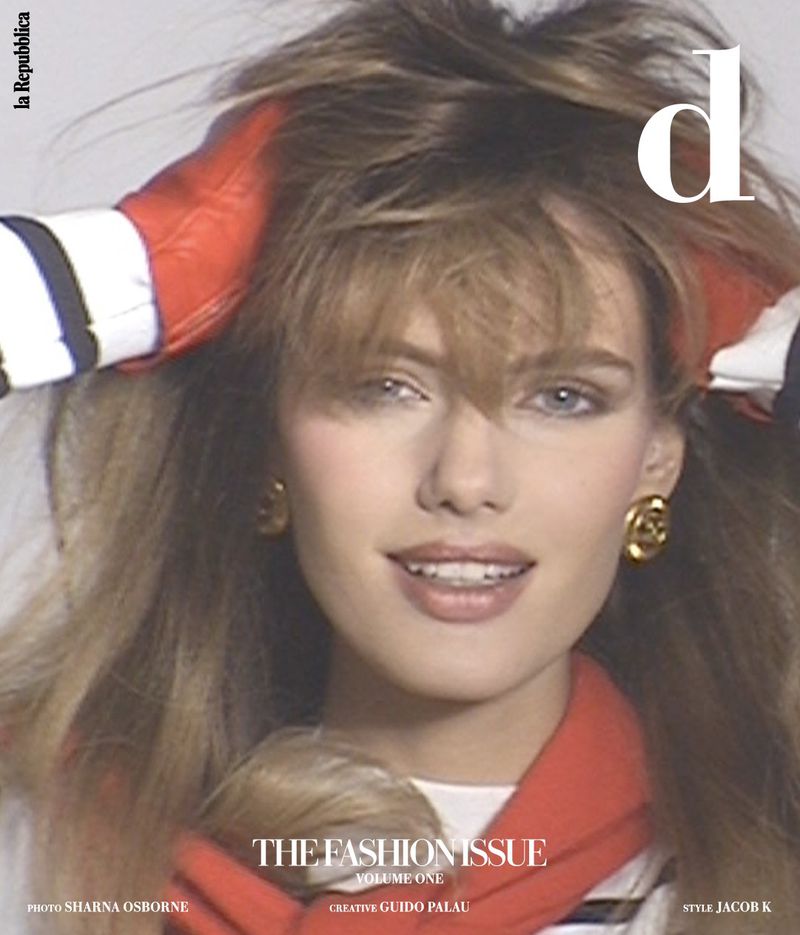 Close-up of a young woman with blonde hair, wearing gold earrings and a red and white jacket, posing for a fashion magazine cover.