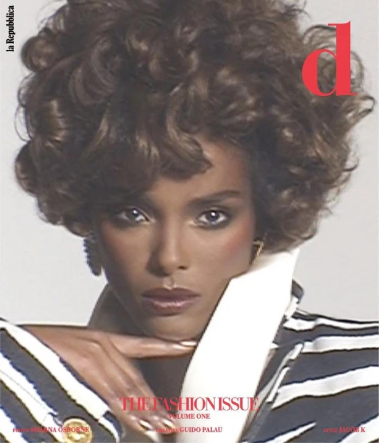 Fashion magazine cover featuring a model with curly brown hair, wearing a striped blazer with a white lapel, looking at the camera.