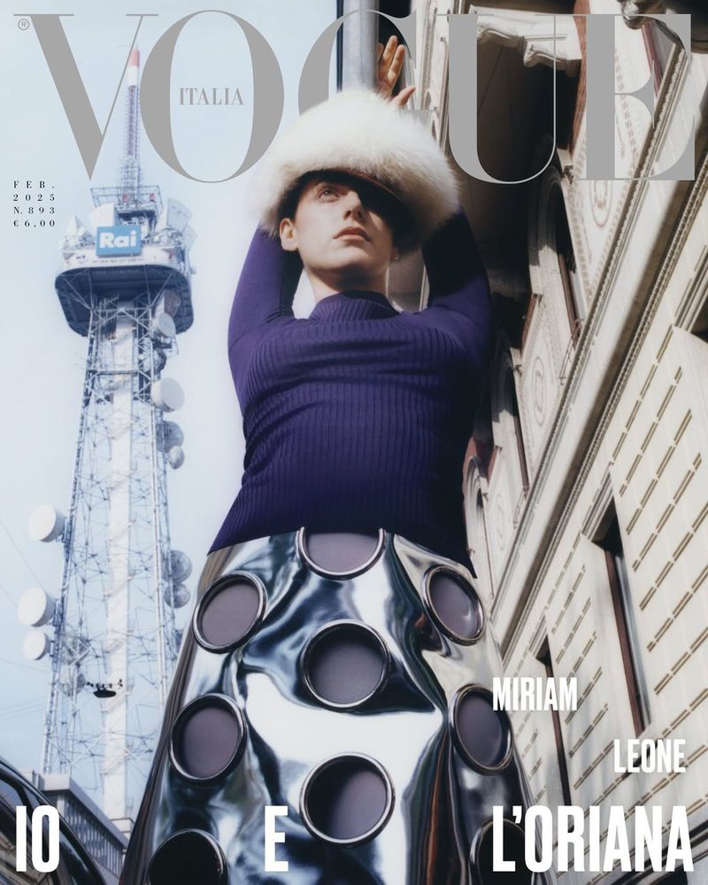 Vogue Italia cover featuring a person in a purple top, metallic skirt, and furry hat, with a tower and urban buildings in the background.