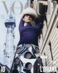 Miriam Leone wearing a white fur hat and purple top against a city tower background for Vogue Italia