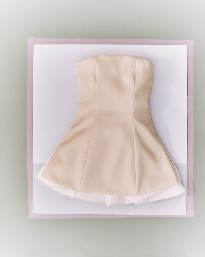 Strapless light beige dress with a white lining, displayed on a white surface with a lavender border, casting a soft shadow.