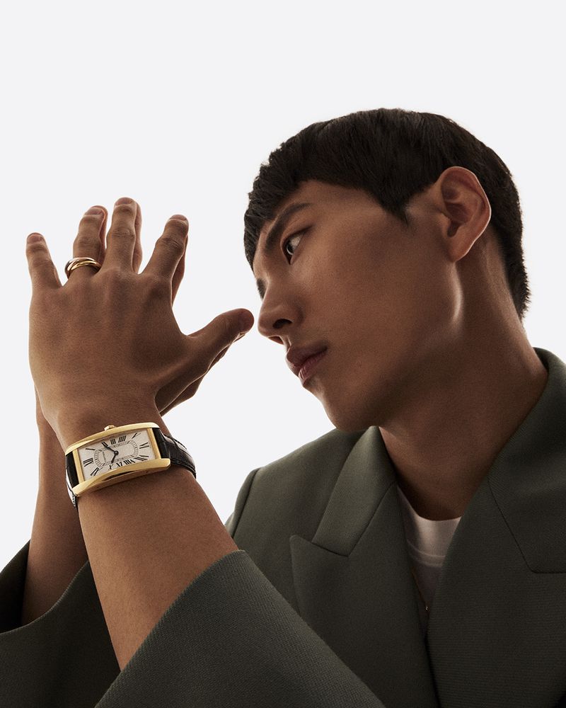 Wristwatch ad featuring a young Asian man in a suit and ring, showcasing fashion and accessorizing against a bright studio backdrop.