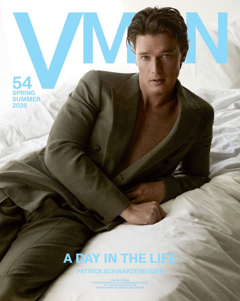 Magazine cover features Patrick Schwarzenegger in a double-breasted suit, posing on a bed with white sheets, soft lighting, and editorial style.