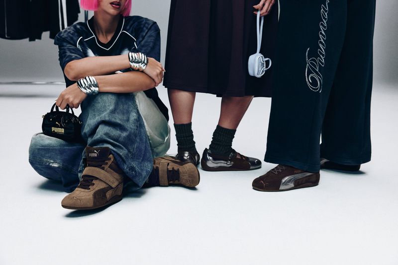 Three women are showcasing Puma shoes and accessories in a studio environment, with a spotlight on their fashionable footwear and coordinated styling.