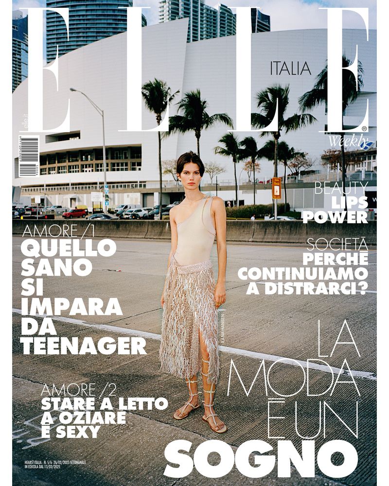 Elle Italia magazine cover featuring a model in a shimmering skirt, shot outdoors against an urban skyline with palm trees and architectural building.