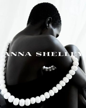 Model Amar Akway wearing a large white beaded necklace against a plain white background for Anna Shelley Fragment Collection 2