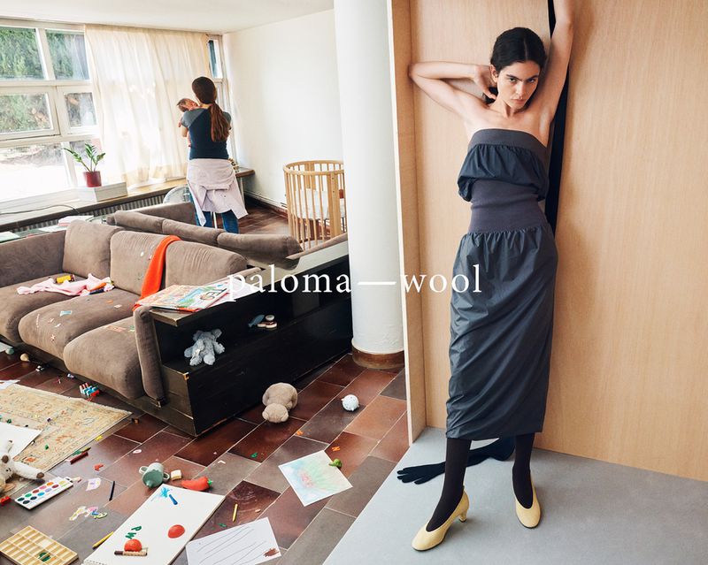 A woman in a gray dress poses next to a wooden wall, juxtaposed with a messy living room scene featuring a woman holding a baby.