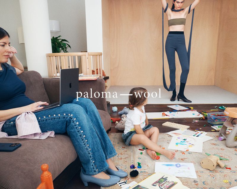 Indoor scene with a woman using a laptop on a brown couch, a girl playing on the floor, and a fashion model posing in the background.