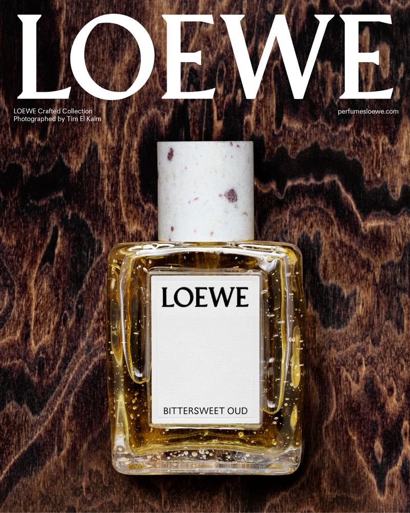 Loewe perfume bottle on a dark wood surface featuring the brand name in bold white text above and the name of the scent below.