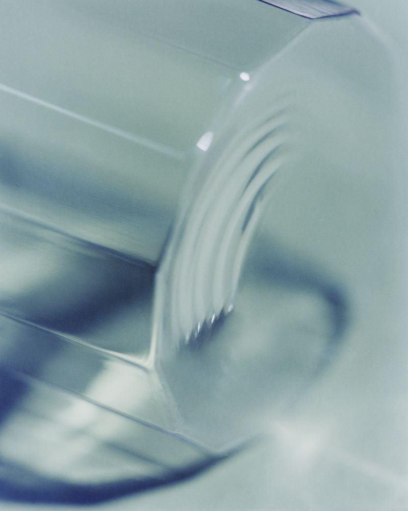 Close-up shot of a clear, geometric glass with a teal hue, emphasizing its textured surface and the play of light and shadow.