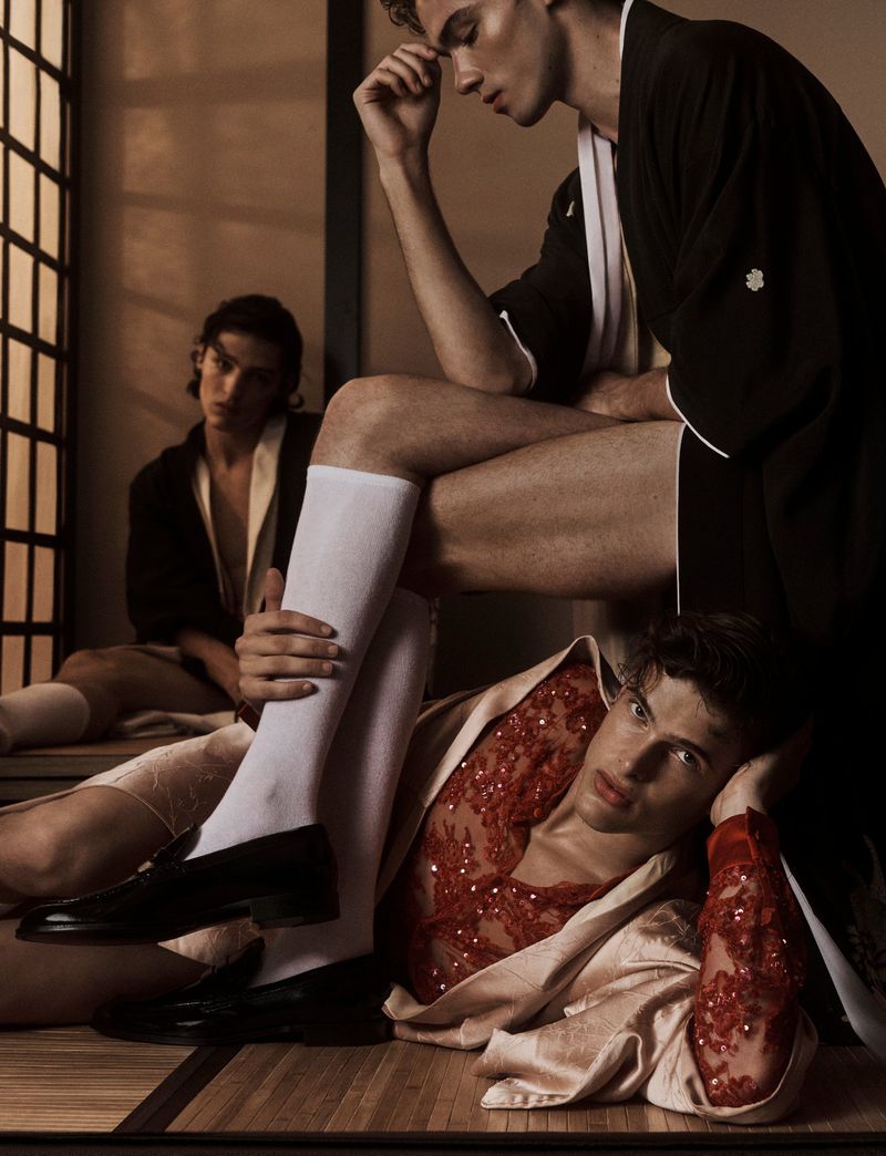 Three young men in kimonos and long socks pose indoors against a shoji screen; one reclines on the floor, with dark loafers.