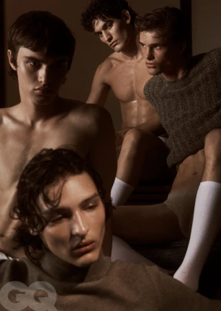 Four male models posing closely in warm, low-key lighting wearing knitwear and loungewear for a menswear editorial.