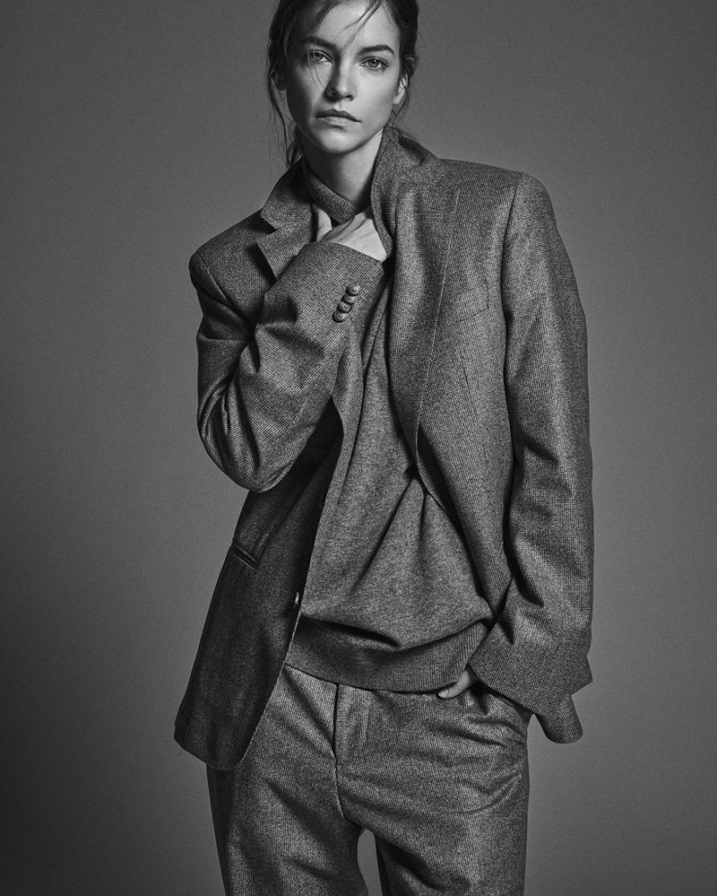 Monochrome portrait of Barbara Palvin posing in an oversized tailored grey suit against a neutral studio backdrop.