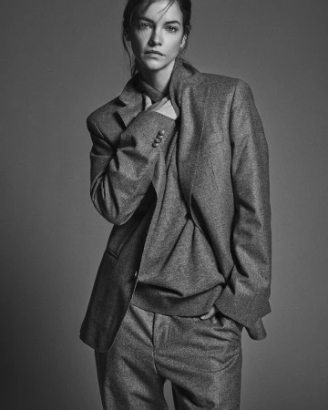 Monochrome portrait of Barbara Palvin posing in an oversized tailored grey suit against a neutral studio backdrop.