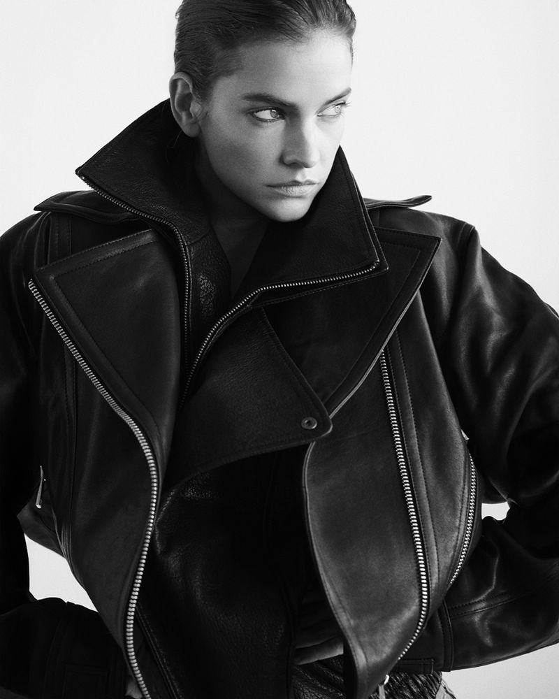 Monochrome portrait of Barbara Palvin wearing an oversized black leather biker jacket with wide lapels against a plain backdrop.