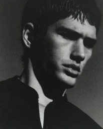 Close-up monochrome portrait of a young man with dark hair in deep shadow and high contrast lighting for UVU project editorial.