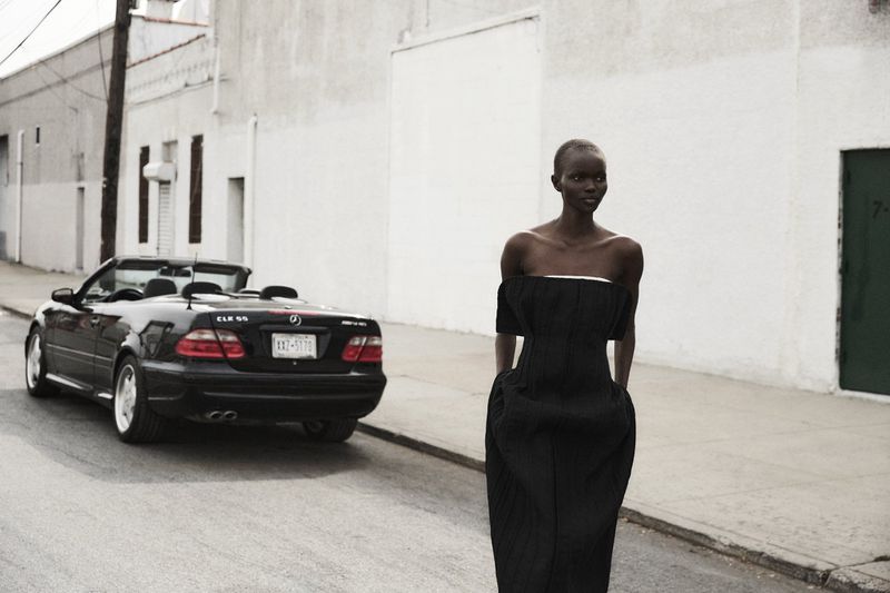 Elegant Black Woman in Designer Dress Poses on City Street Next to Black Mercedes-Benz Convertible, Fashion Editorial Photography.