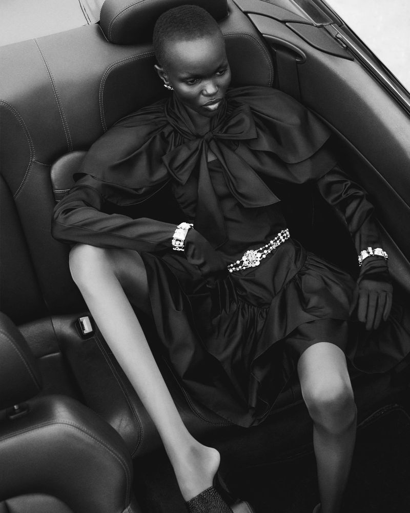 Elegant woman poses in black dress and jewelry inside of convertible car, monochrome image. Fashion shot with luxury feel.