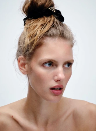 Model Rosalieke Fuchs with a textured messy bun held by a black scrunchie against a bright white background.