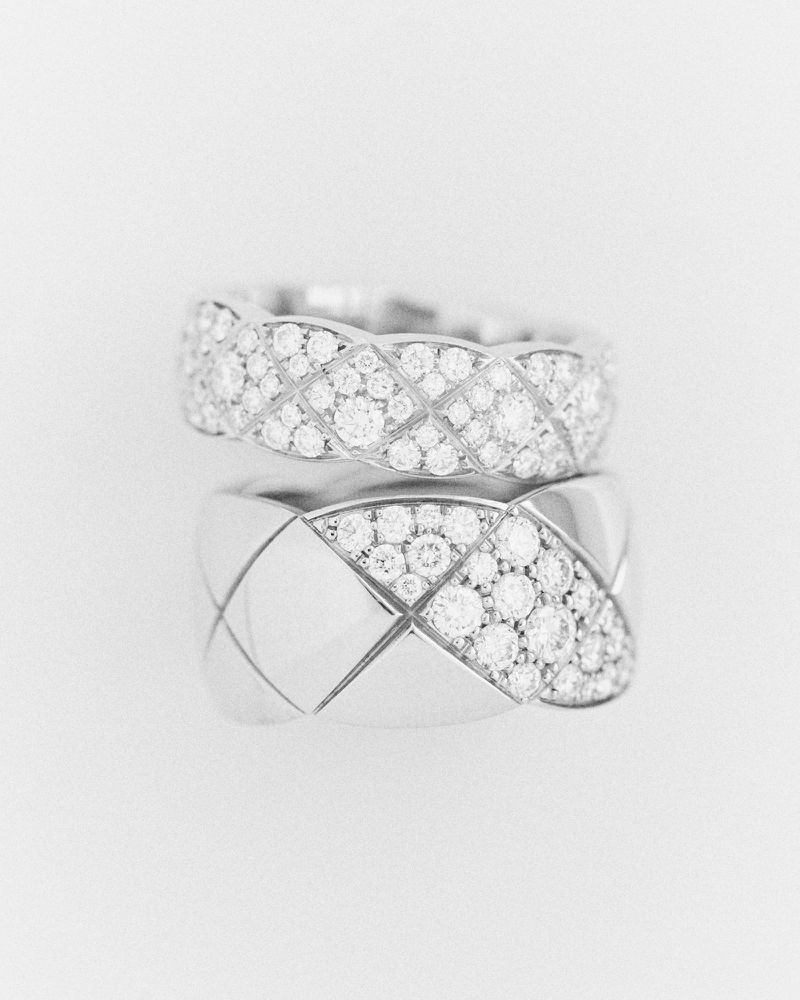 Close-up of two wide platinum diamond pave rings with geometric lattice design, resting on a clean white background, jewellery still life.
