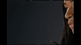 Profile view of adult female with dreadlocks against dark backdrop, showcasing beauty lighting and personal style.