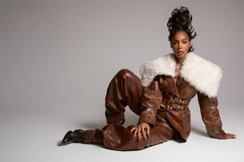 Elegant woman in a brown patterned suit with a white fur collar posing against a neutral background in a fashion photography setting.