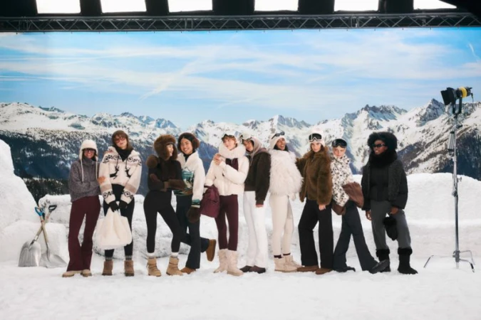 Group of nine diverse women models pose outdoors in winter apparel with snow and mountain backdrop. Photo studio lighting and snow props.