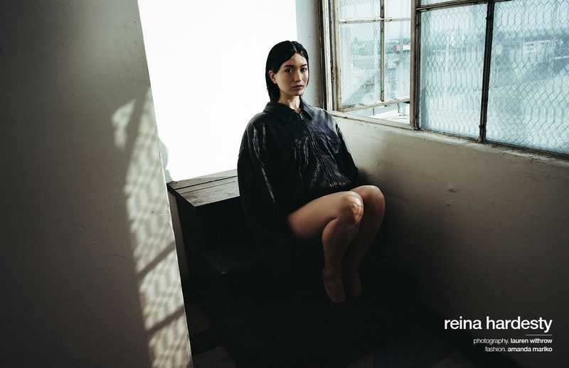 Woman in a black leather jacket sitting on stairs by a window for Schön Magazine, photographed by Lauren Withrow.