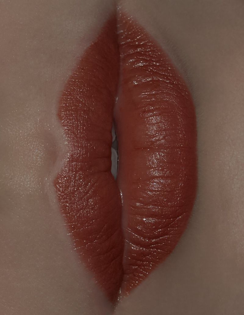 Close-up of woman's lips with vibrant red lipstick, highlighting texture and form in soft, diffused lighting for beauty concept.