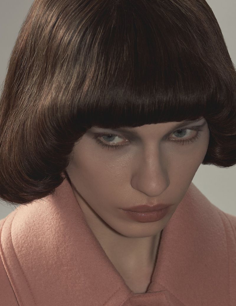 Close-up portrait of model Kate Letskaya with a blunt brunette bob hairstyle wearing a dusty pink wool coat.