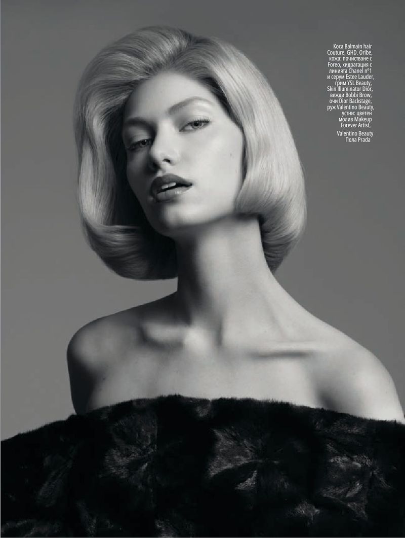 Black and white beauty portrait of a woman with a sculpted retro bob hairstyle wearing an off-the-shoulder textured black stole.