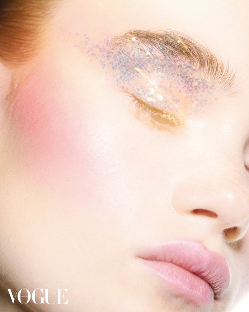 Closeup of woman's face with eyes closed and glitter eyeshadow. Makeup and beauty shot with soft, even lighting and focus on facial details.