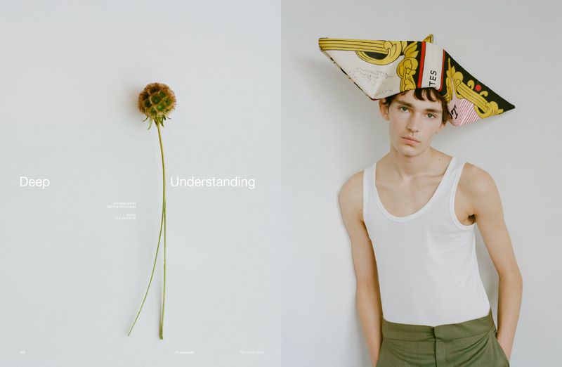 Artistic studio shot: young man wearing a scarf as headwear alongside a unique flower on a contrasting clean backdrop.