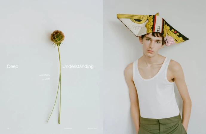 Artistic studio shot: young man wearing a scarf as headwear alongside a unique flower on a contrasting clean backdrop.