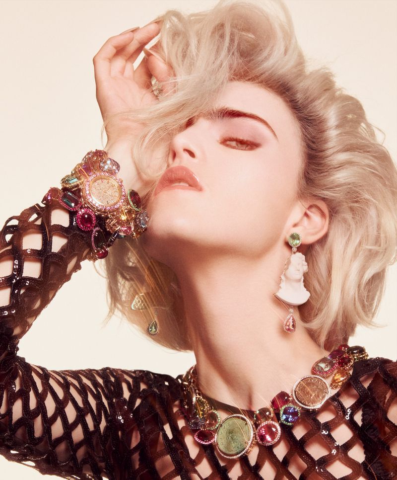Elegant woman with striking blonde hair and elaborate jewelry, showcasing a high-fashion look in a close-up studio shot.