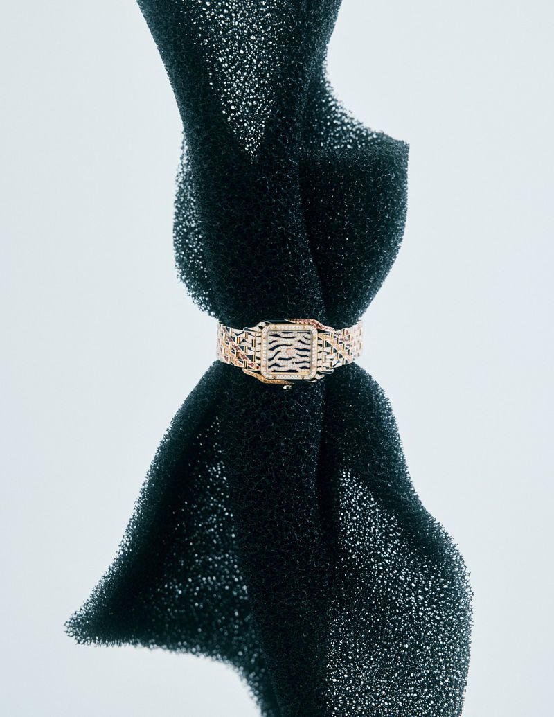 Close-up of an animal print buckle bracelet on dark porous sponge with studio lighting, showcasing jewelry design.
